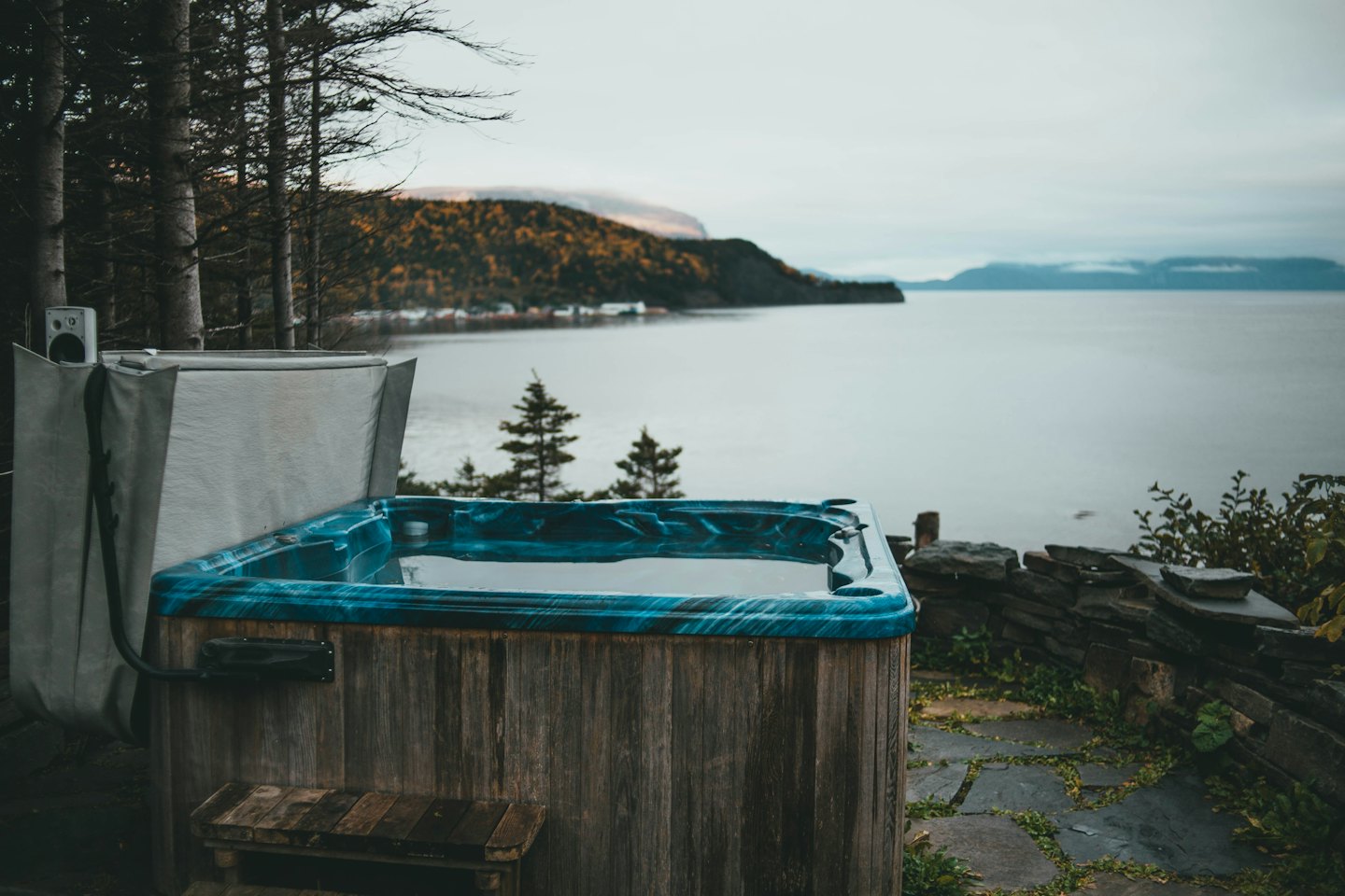 Hot tub on flagstone patio overlooks water and mountains.
